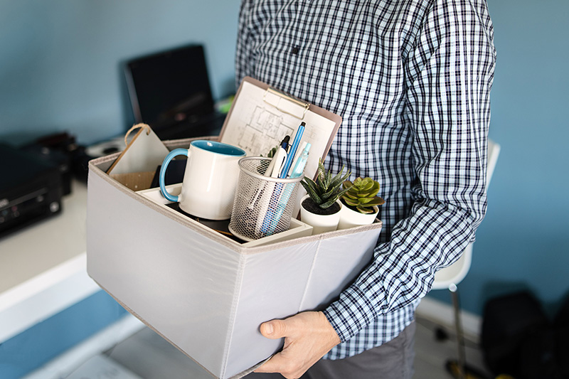 man holding a box with personal items leaving the office after being fired from work due recession economic crisis downturn