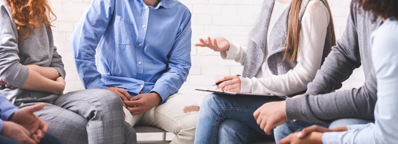 Mentor discussing problem with therapy group members at meeting in rehab