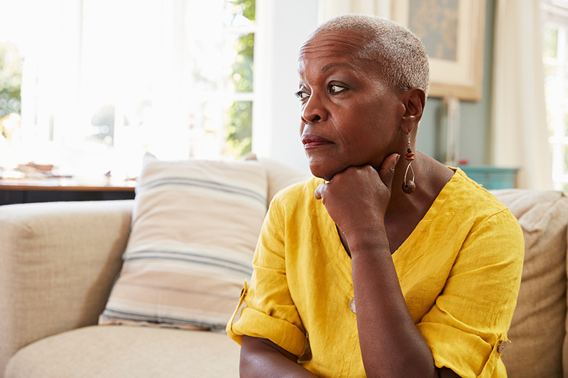 Senior African American woman sitting on sofa suffering from depression