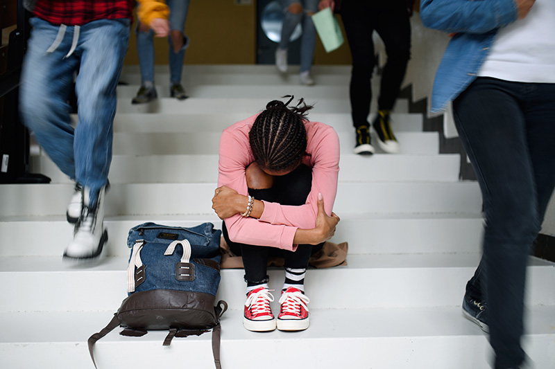 Depressed young student with head down sitting on steps